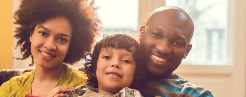 Family smiling and sitting on couch 