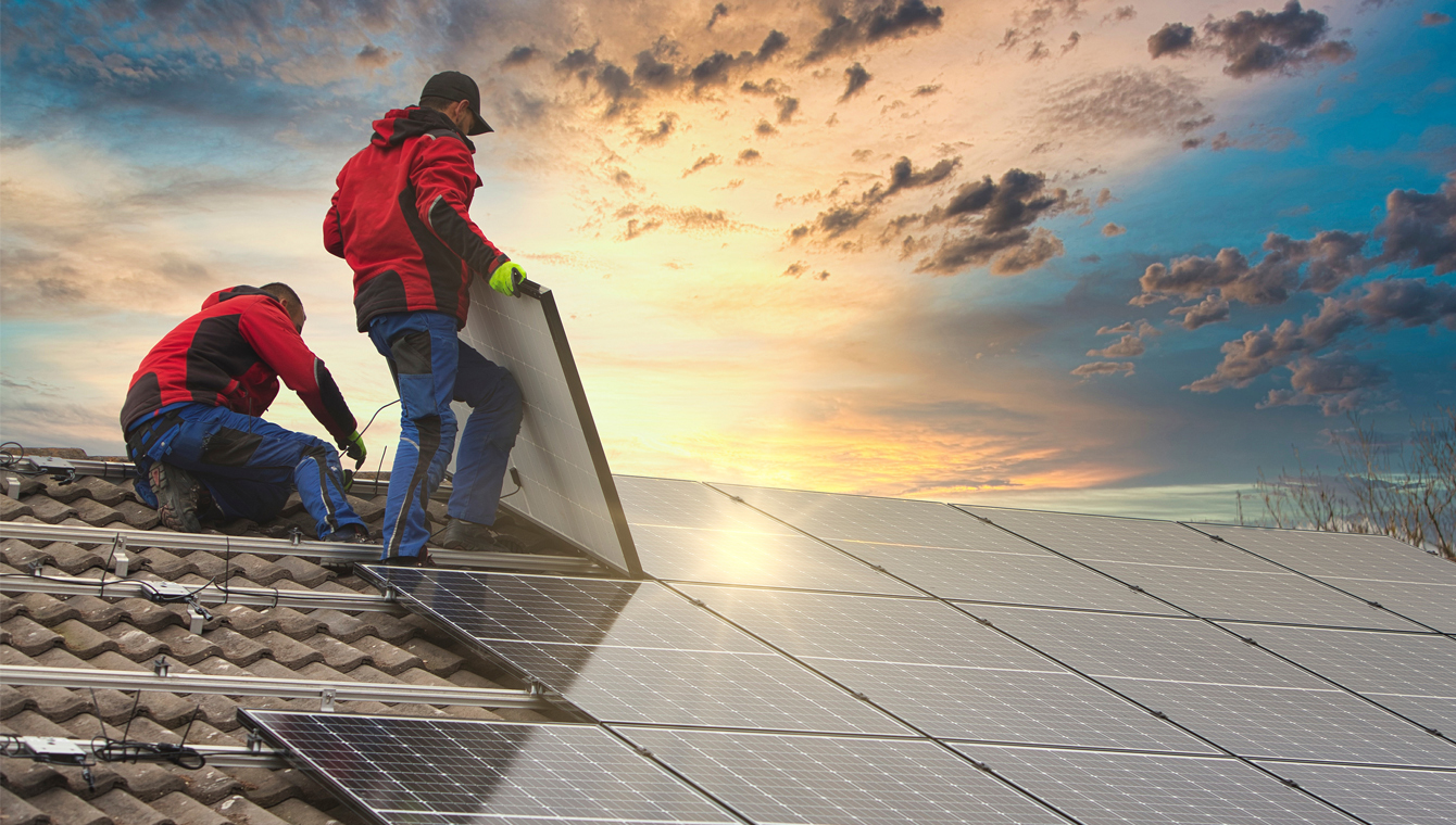 men on a roof setting up solar panels